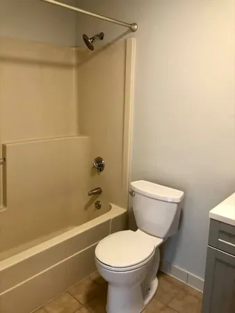 a white toilet sitting next to a bath tub and a shower