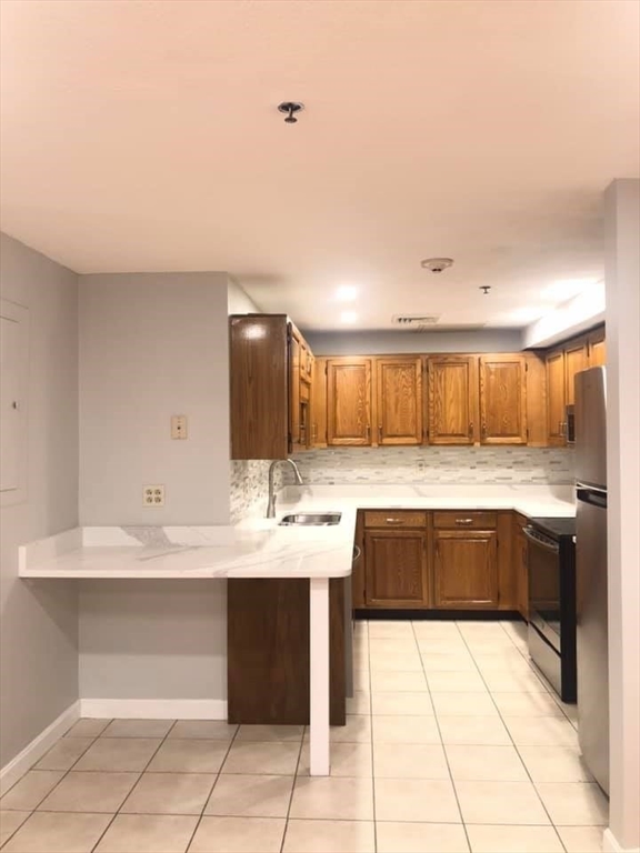 39 Parlin Street, Unit 203 Everett, MA 02149 - Photo 4 of 20 a kitchen with kitchen island granite countertop a sink and white cabinets
