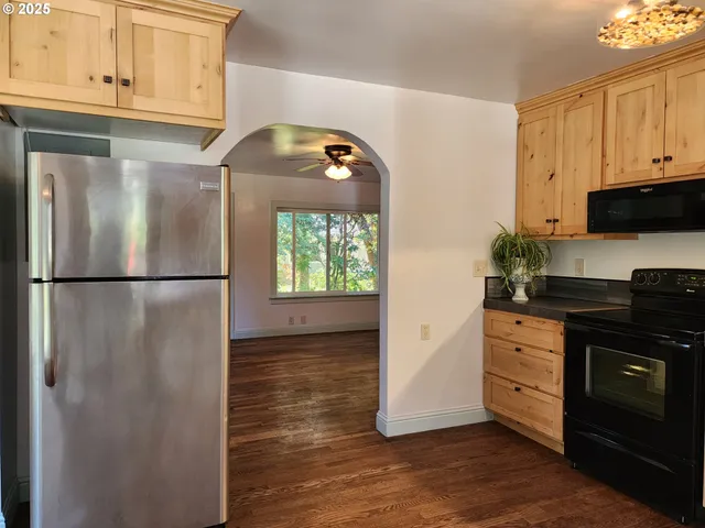 a view of a kitchen with a fridge wooden floor cabinet and a window