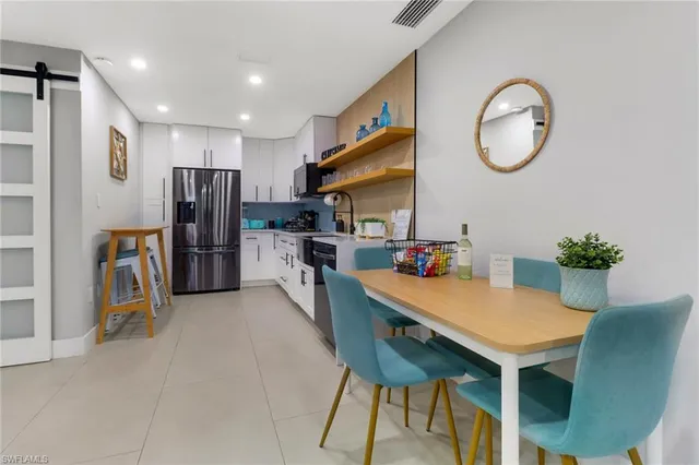a view of kitchen with stainless steel appliances granite countertop dining table chairs and a refrigerator
