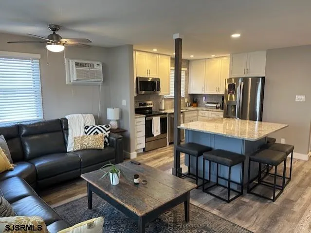 a living room with stainless steel appliances kitchen island granite countertop furniture and a view of kitchen