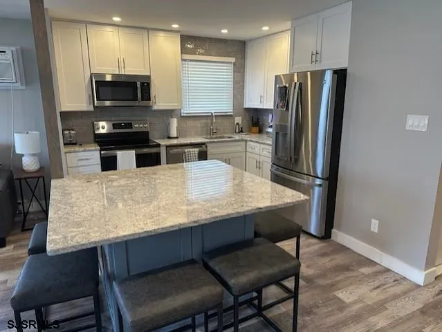 a kitchen with stainless steel appliances wooden floor and chairs