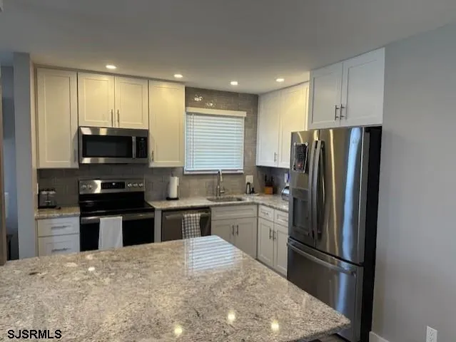 a kitchen with stainless steel appliances granite countertop a refrigerator stove microwave and sink