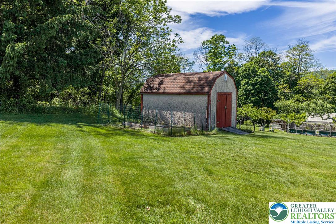 947 Tamenend Road Bath, PA 18014 - Photo 46 of 61 A quaint storage shed nestled amidst lush green lawn and mature trees, perfect for outdoor equipment.