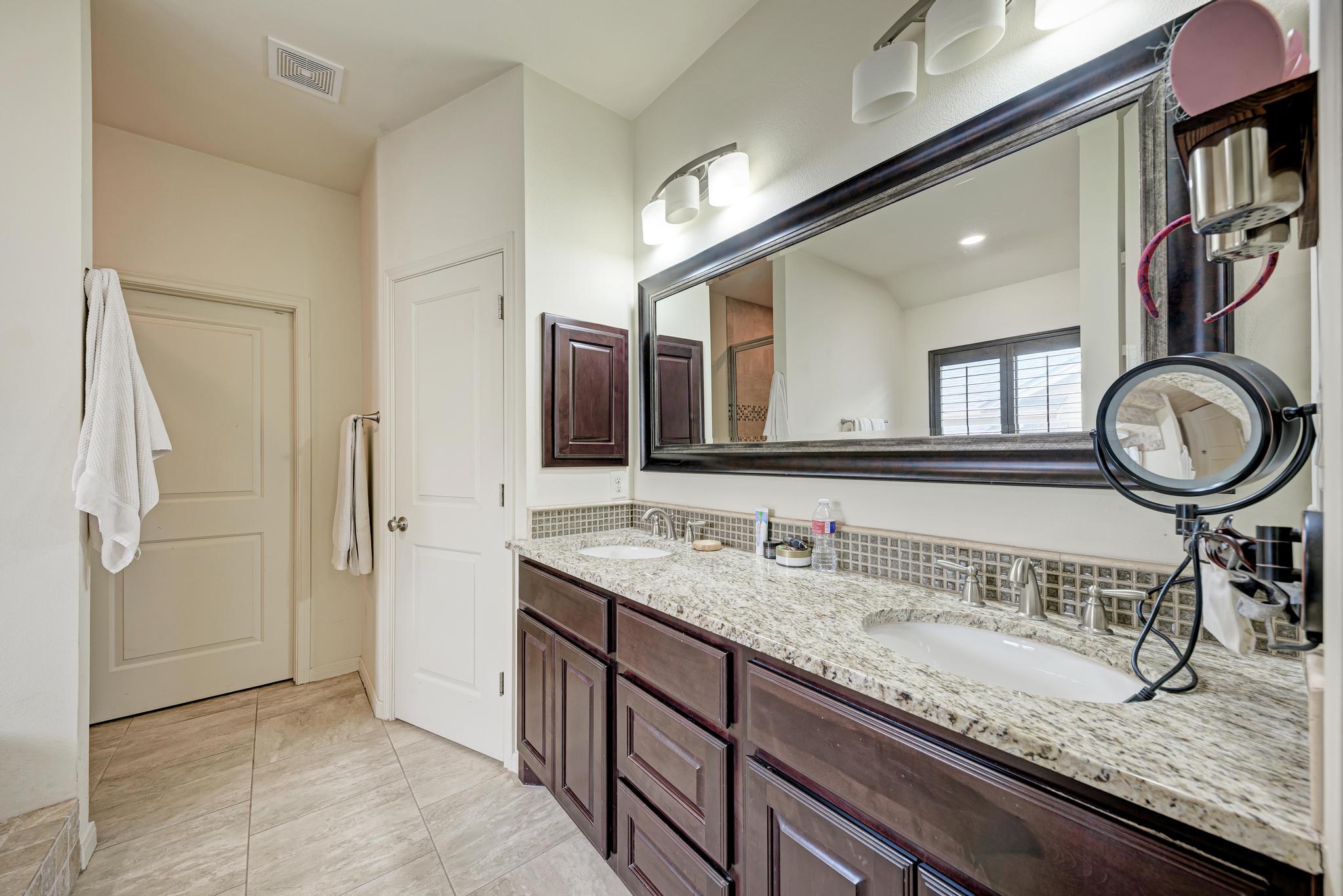 2605 Indian Creek Road Austin, TX 78734 - Photo 14 of 33 Double vanity featuring granite countertops with undermount sinks, espresso-finish cabinetry, and a full-width framed mirror