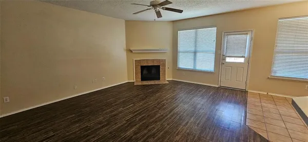 an empty room with wooden floor fireplace and windows