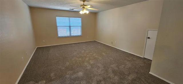 an empty room with windows and chandelier fan