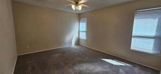 an empty room with windows and fan