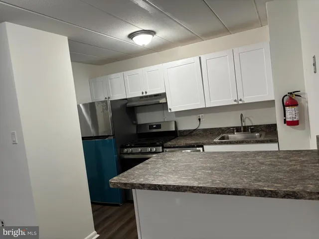 a kitchen with granite countertop a sink a stove and a refrigerator