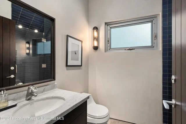 a bathroom with a sink vanity mirror and toilet