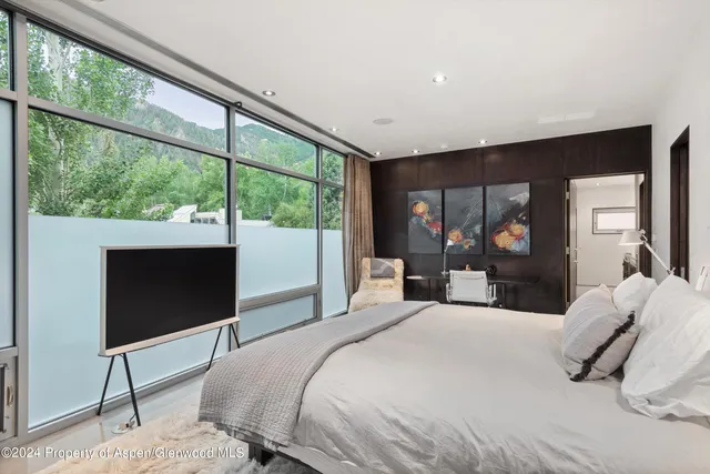 a bedroom with a large bed and a flat tv screen on dresser