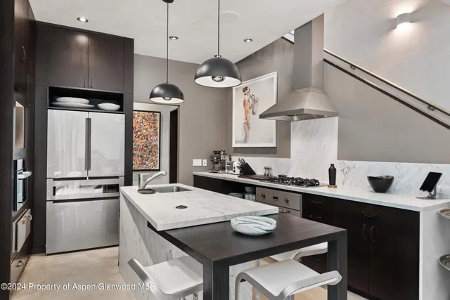 a kitchen with stainless steel appliances a sink a stove a refrigerator a dining table and chairs