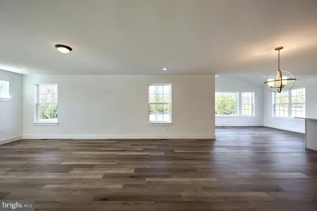 a view of an empty room with wooden floor fireplace and a window