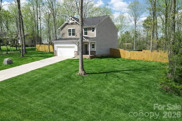 a house that is sitting in the grass and the view of trees in the background