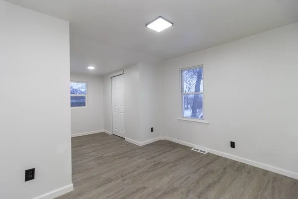an empty room with wooden floor and windows