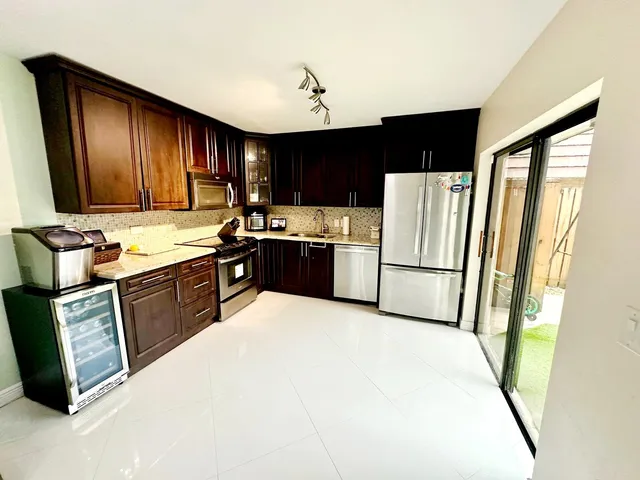 a kitchen with stainless steel appliances granite countertop a refrigerator a stove top oven a sink and dishwasher
