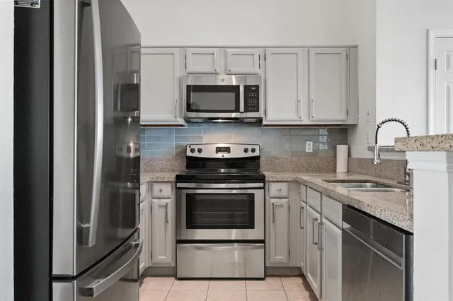 a kitchen with stainless steel appliances granite countertop a stove microwave and sink