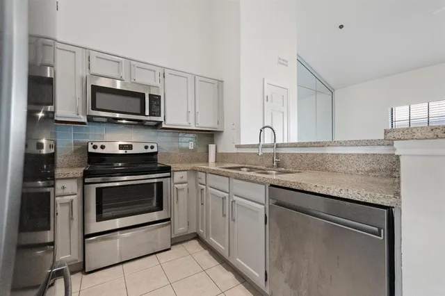 a kitchen with stainless steel appliances granite countertop a sink dishwasher a stove and a microwave oven with cabinets