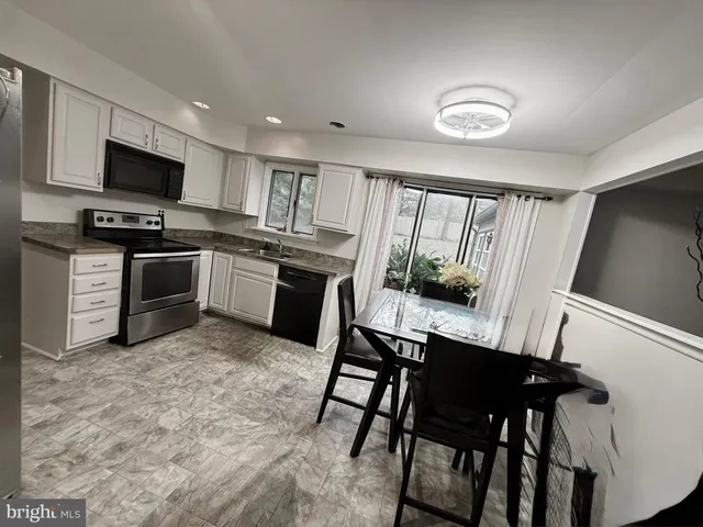 a kitchen with stainless steel appliances granite countertop a stove top oven a sink a dining table and chairs