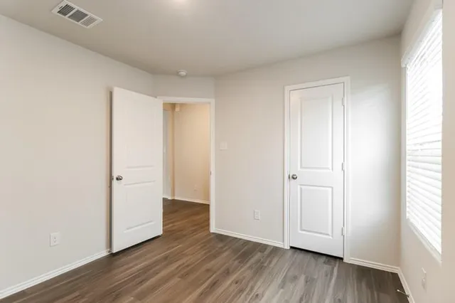 an empty room with wooden floor & windows