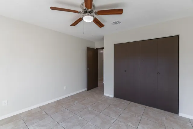 an empty room with closet and a chandelier fan