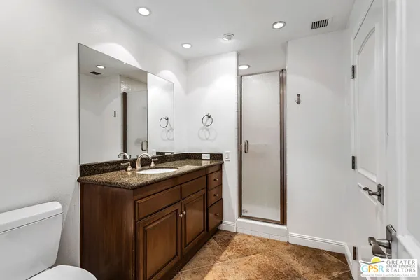 a bathroom with a granite countertop sink a toilet a mirror and shower