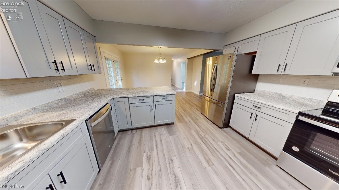 1715 Chenango Road Wakeman, OH 44889 - Photo 10 of 21 Kitchen featuring pendant lighting, tasteful backsplash, stainless steel appliances, gray cabinets, and light wood-type flooring