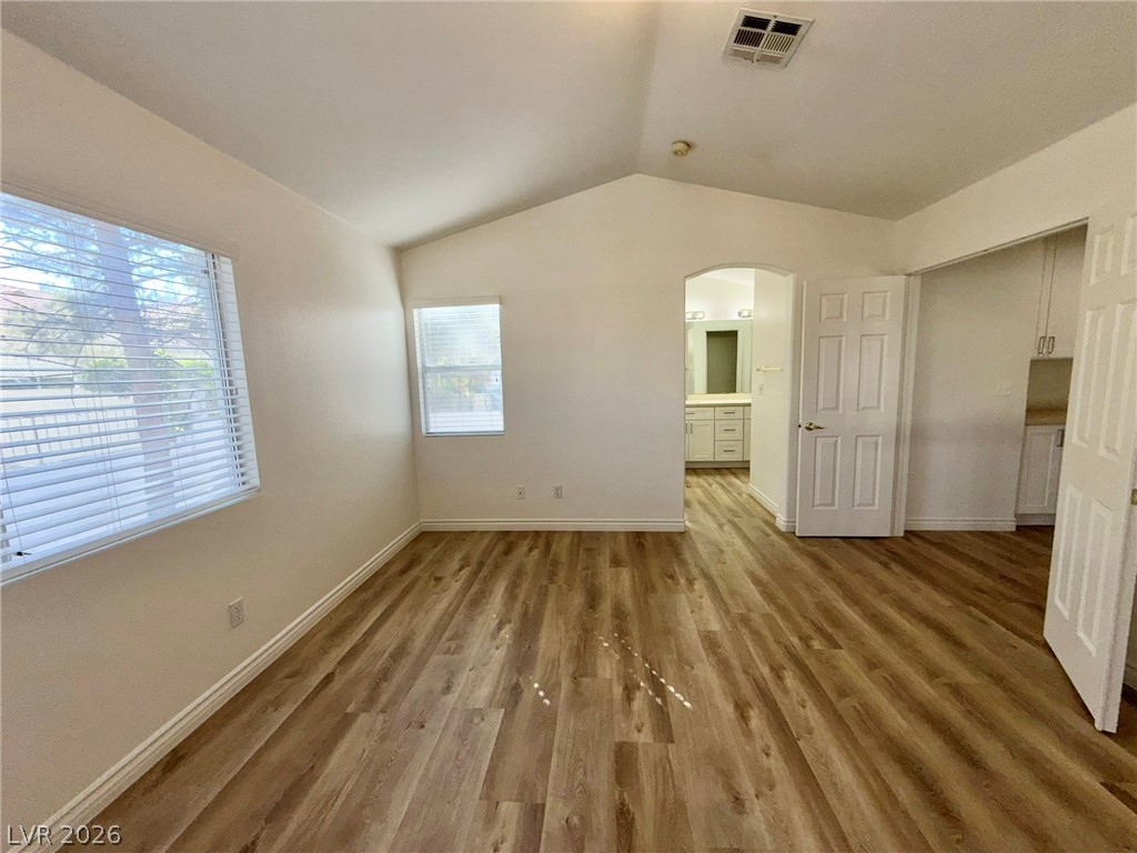 9729 Trail Rider Drive Las Vegas, NV 89117 - Photo 15 of 26 A well-lit primary bedroom features durable hardwood flooring and a vaulted ceiling.