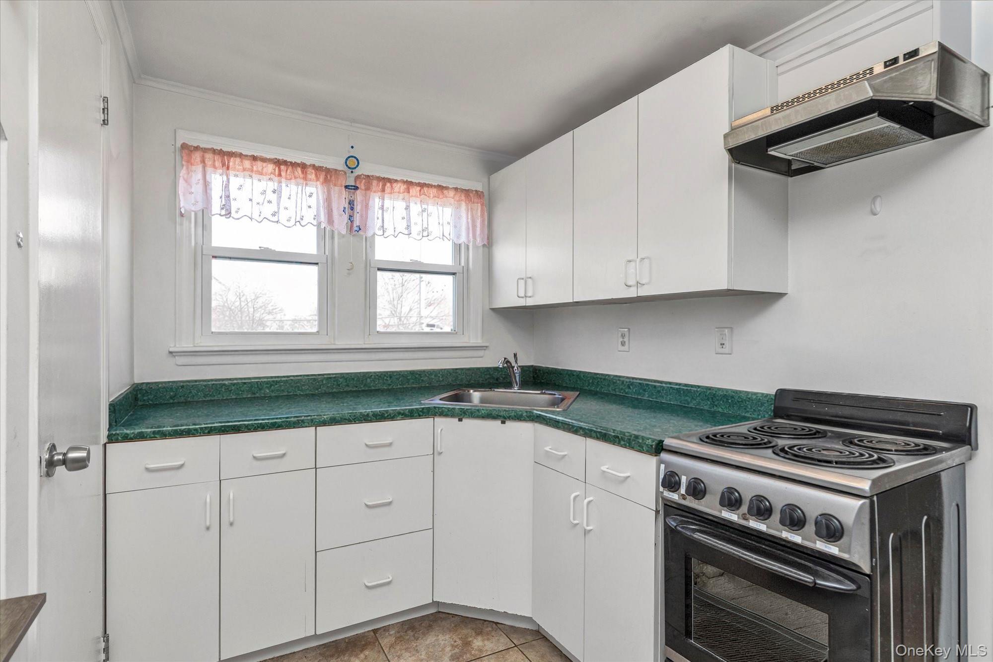 81 Stuart Street Lynbrook, NY 11563 - Photo 15 of 23 a kitchen with granite countertop a stove a sink and dishwasher with white cabinets