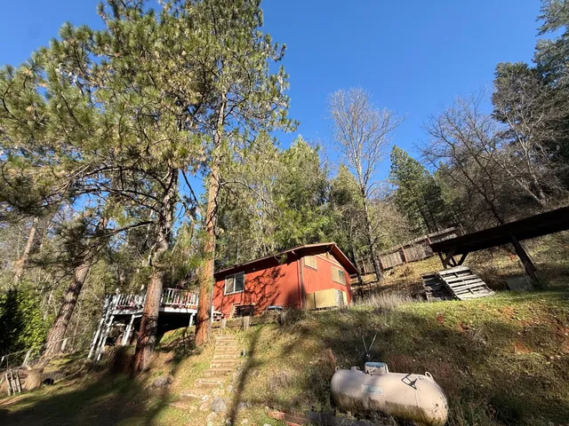 a backyard of a house with table and chairs under an umbrella