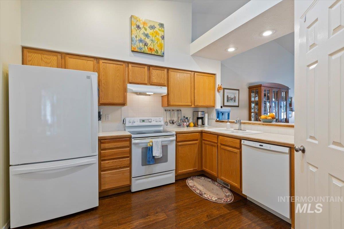 3357 West Fieldstream Lane Meridian, ID 83646 - Photo 11 of 24 Kitchen with white appliances, dark wood-type flooring, wood finish cabinets, tasteful backsplash, and a high ceiling