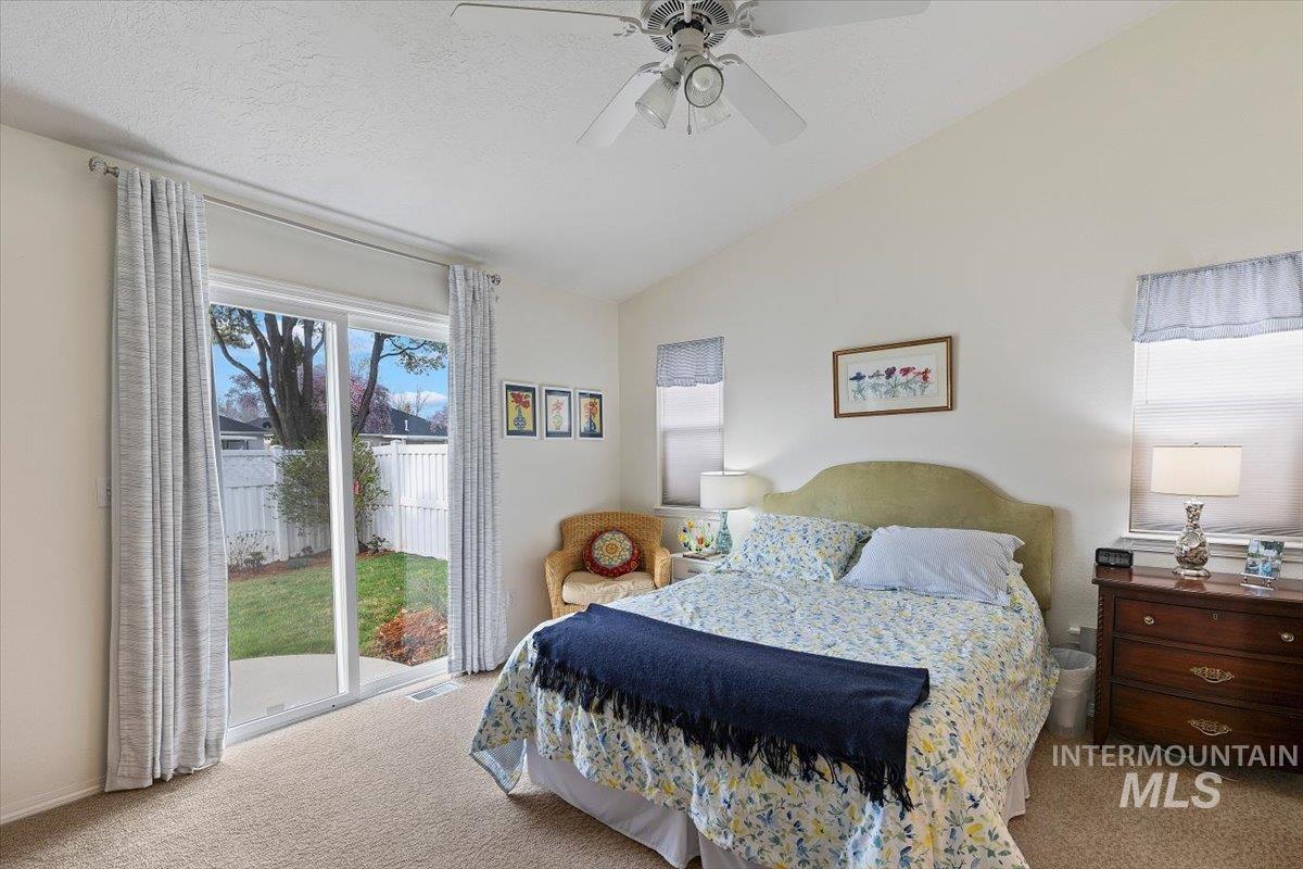 3357 West Fieldstream Lane Meridian, ID 83646 - Photo 15 of 24 Bedroom featuring light carpet, access to exterior, vaulted ceiling, and a ceiling fan