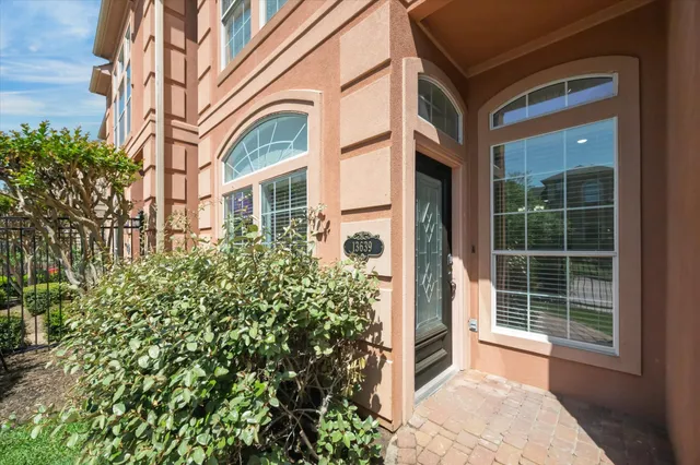 front view of a brick house with a large window and potted plants
