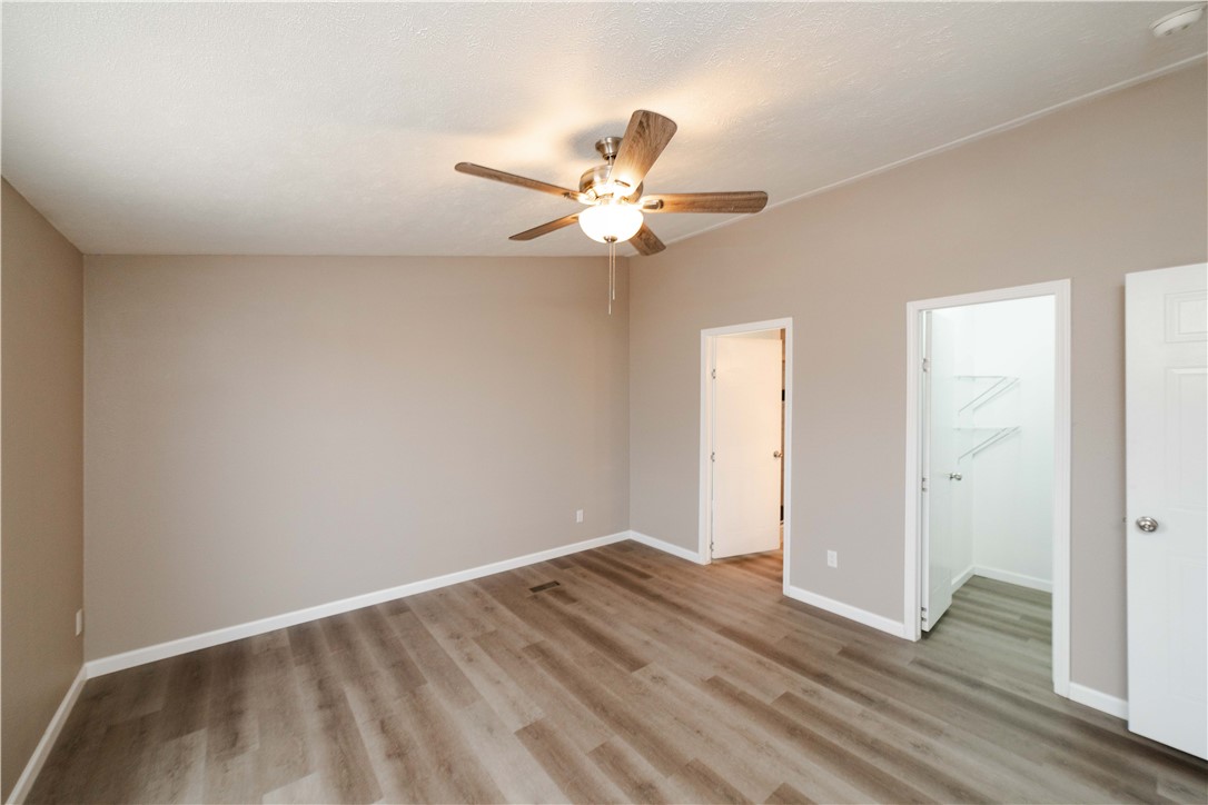 3248 West Carmichael Road Golden Valley, AZ 86413 - Photo 20 of 53 Unfurnished bedroom featuring a walk in closet, light wood finished floors, and ceiling fan