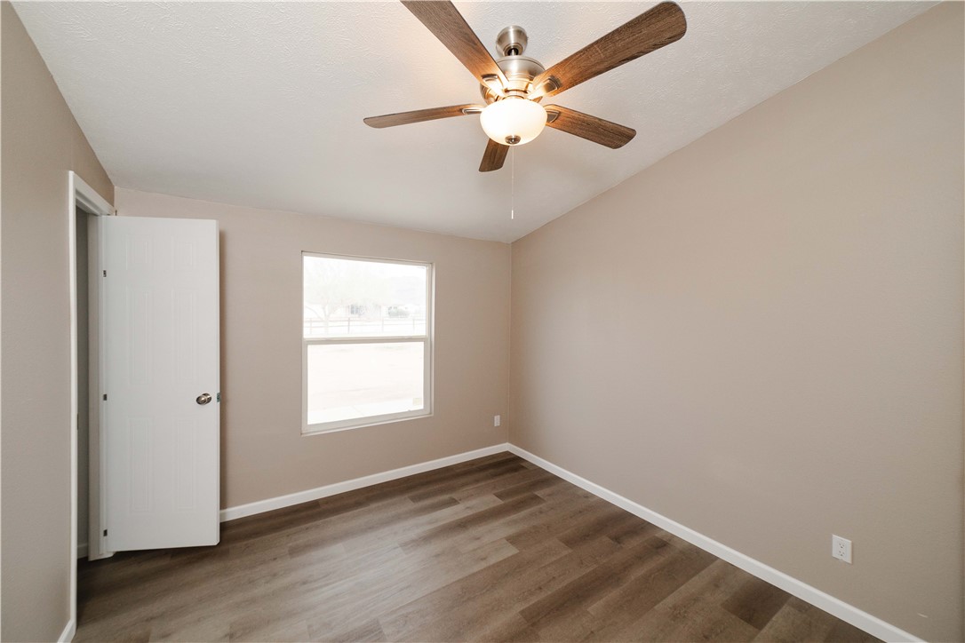 3248 West Carmichael Road Golden Valley, AZ 86413 - Photo 26 of 53 Unfurnished bedroom featuring wood finished floors and a ceiling fan