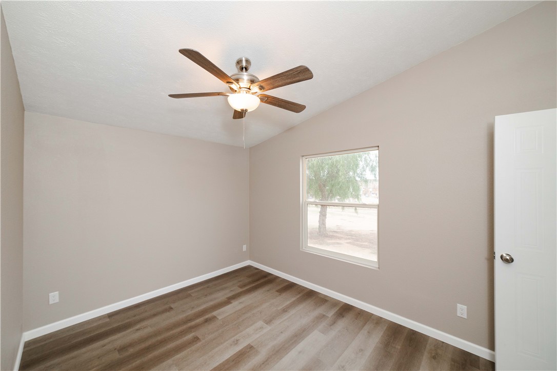3248 West Carmichael Road Golden Valley, AZ 86413 - Photo 29 of 53 Unfurnished room with light wood-type flooring, lofted ceiling, and a ceiling fan