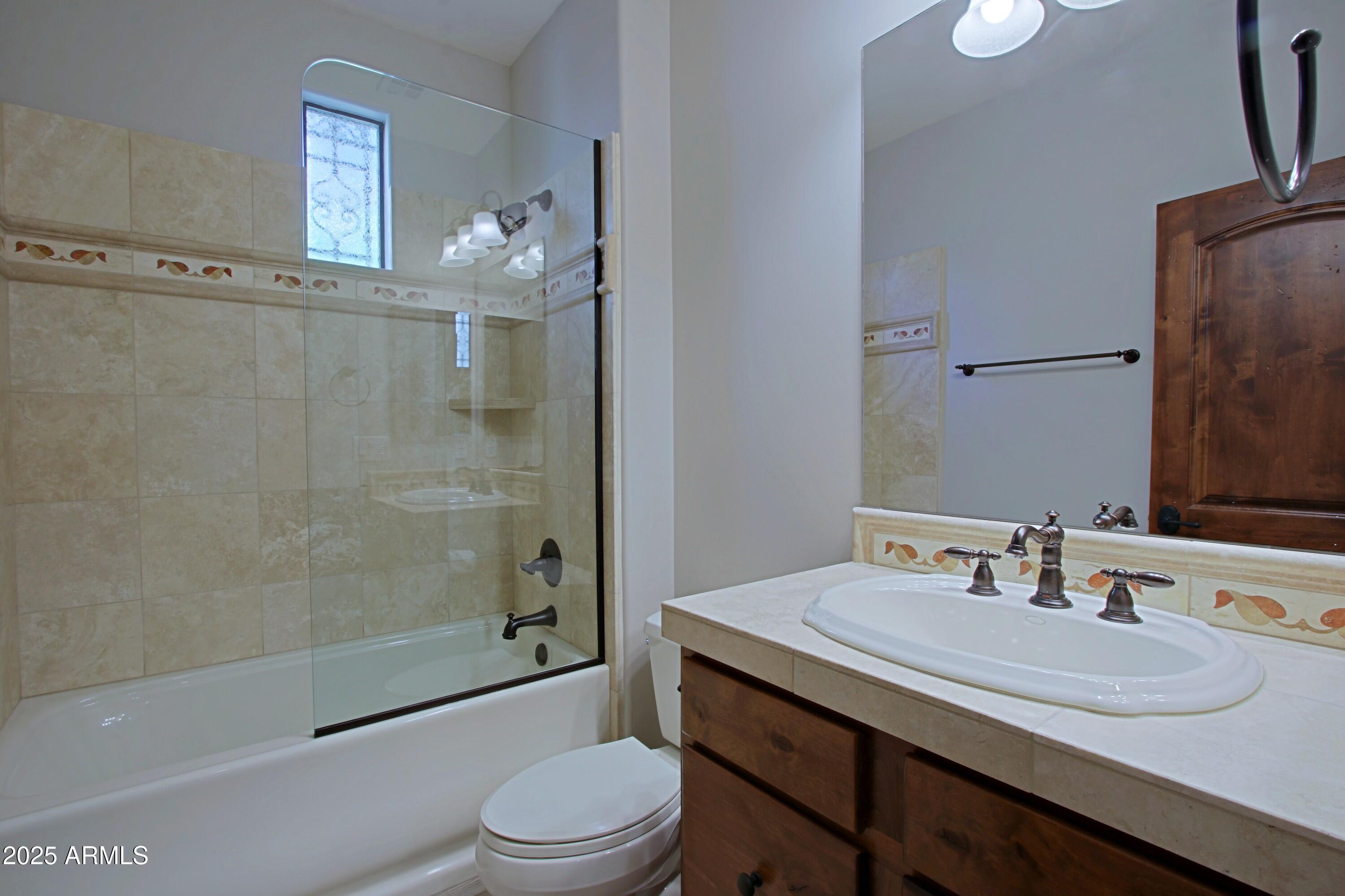 18650 North Thompson Peak Parkway, Unit 1052 Scottsdale, AZ 85255 - Photo 20 of 38 a bathroom with a granite countertop sink toilet a mirror and shower