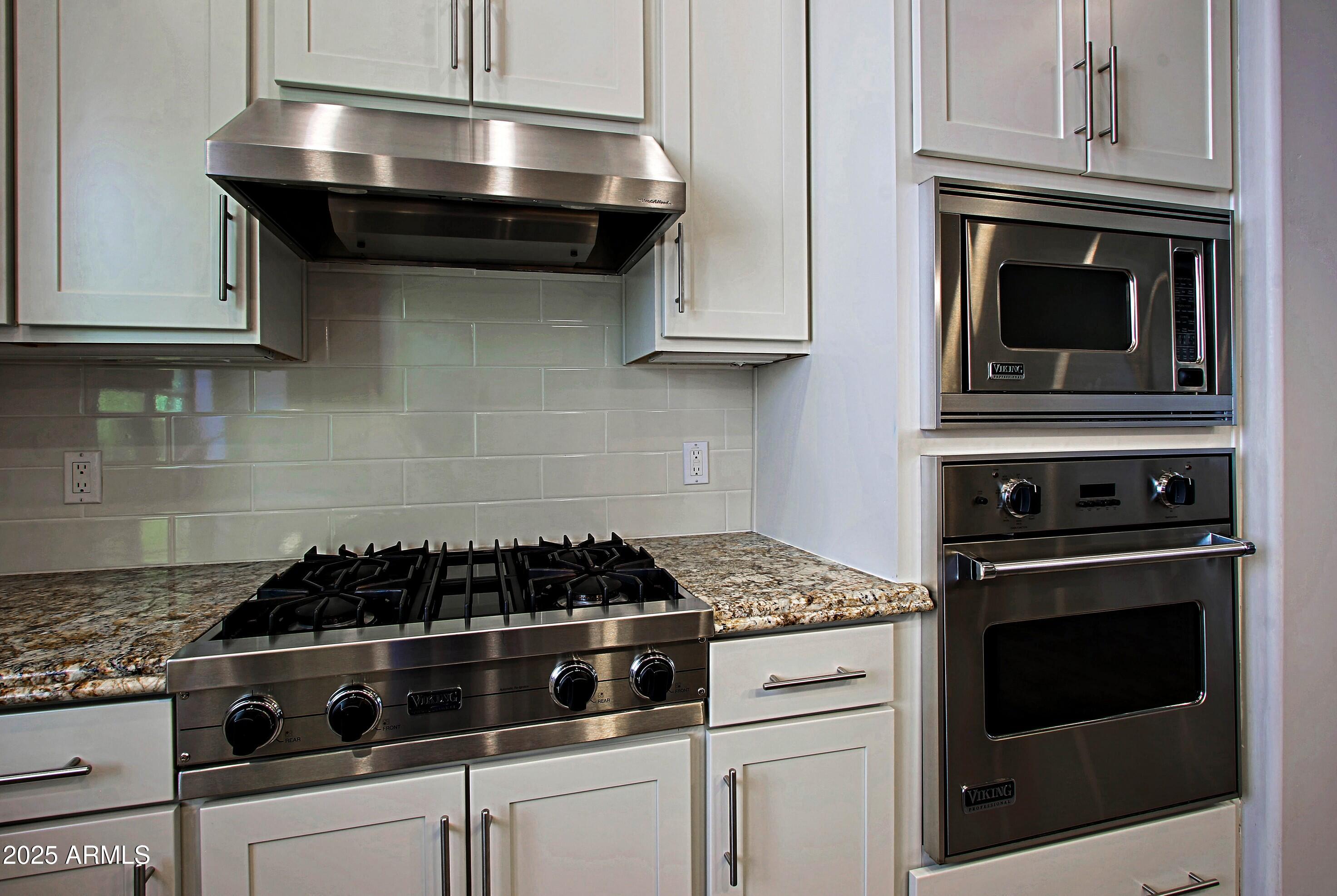 18650 North Thompson Peak Parkway, Unit 1052 Scottsdale, AZ 85255 - Photo 6 of 38 a kitchen with stainless steel appliances granite countertop white cabinets and black stove top oven with granite countertops