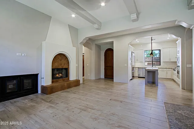 a view of empty room with kitchen and fireplace