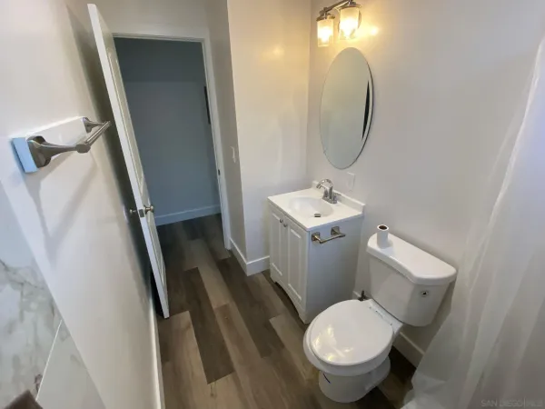 a white toilet sitting next to a bathroom sink and a mirror