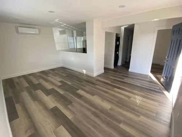 a view of an empty room with wooden floor and a window