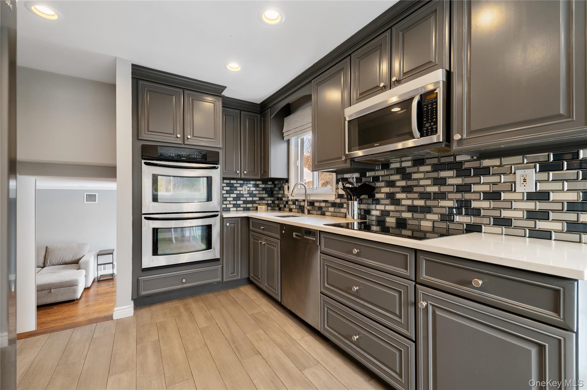 7 Rita Lane Plainview, NY 11803 - Photo 12 of 30 Kitchen featuring stainless steel appliances, light wood-style flooring, recessed lighting, gray cabinetry, and backsplash