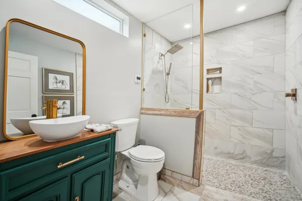 a bathroom with a granite countertop sink a toilet a mirror and shower