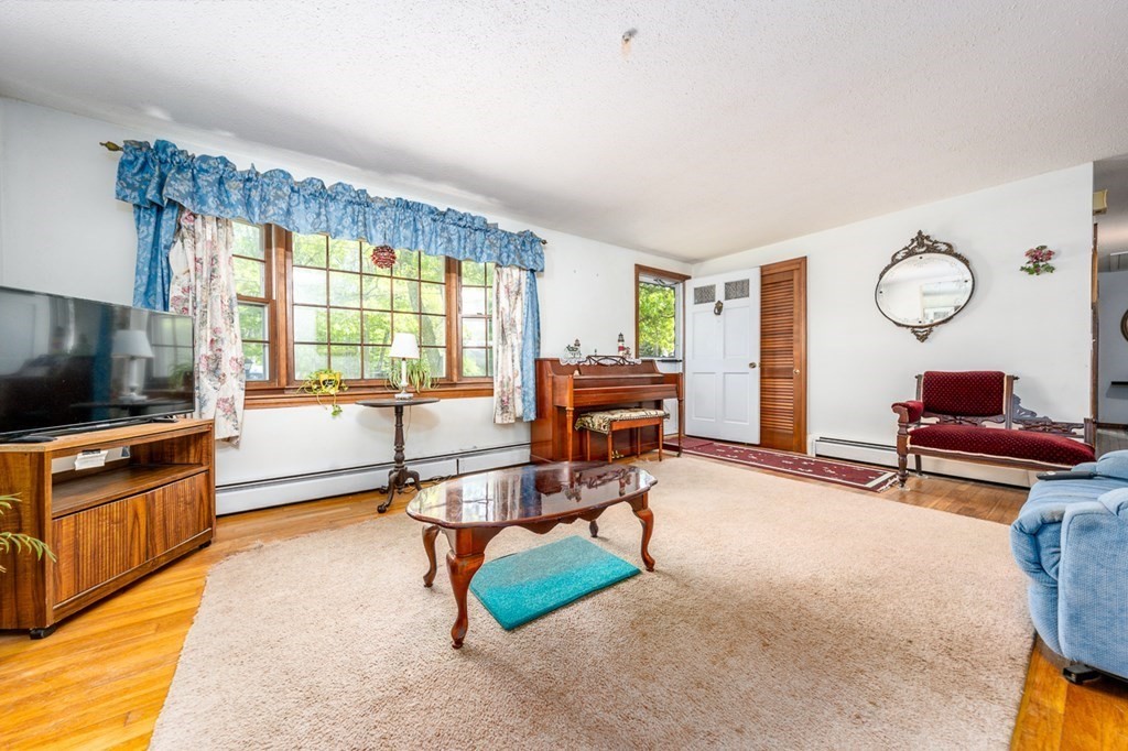 231 Monomoy Circle Barnstable, MA 02632 - Photo 8 of 28 a living room with furniture a flat screen tv and a large window