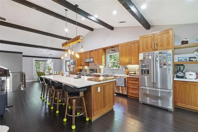 a kitchen with a refrigerator a stove a sink dishwasher and a dining table with wooden floor