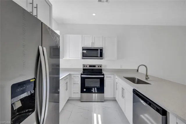 a kitchen with stainless steel appliances white cabinets and a sink