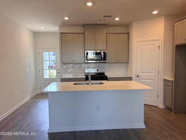 a large kitchen with stainless steel appliances a large counter top and a stove top oven