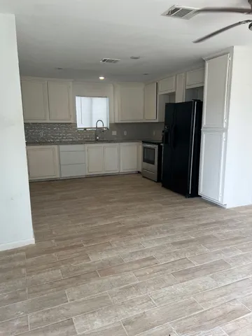 a view of kitchen with refrigerator cabinets and wooden floor