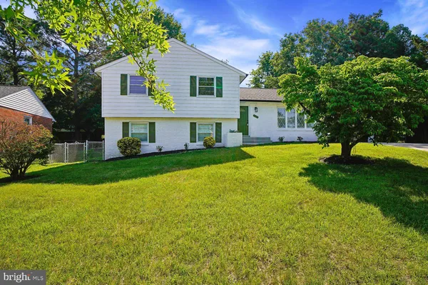 a view of a house with a big yard and large trees