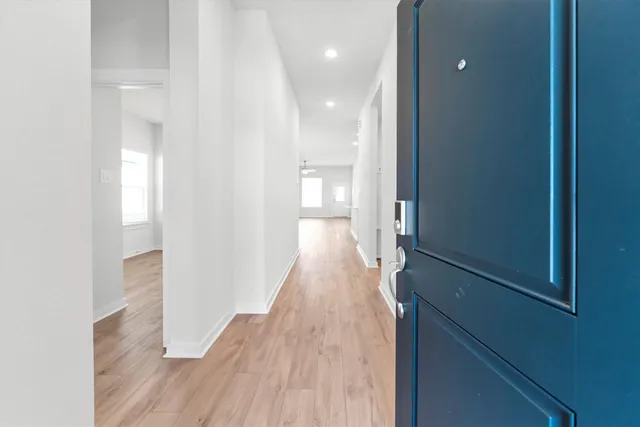 a view of a hallway with wooden floor and a bathroom